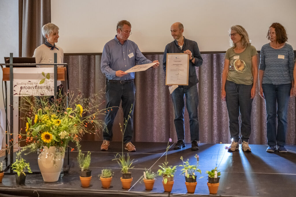 Carl Binding übergibt die Urkunde und den Check an den Quartiergarten Hard