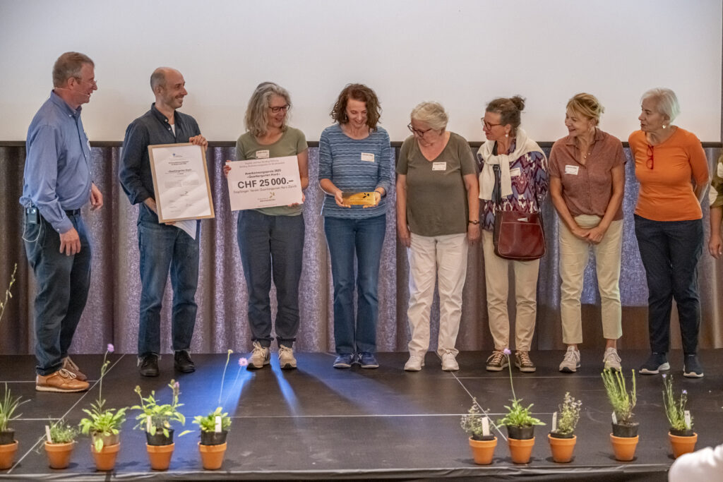 Carl Binding übergibt die Urkunde und den Check an den Quartiergarten Hard
